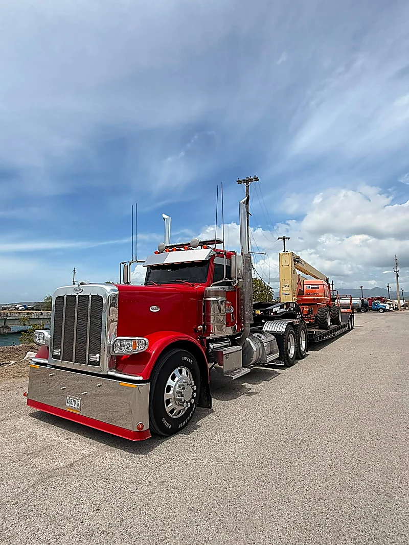 Lowboy con boom lift en una zona portuaria